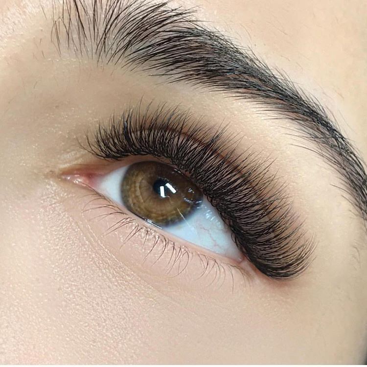 Close-up van een bruin oog met volle, donkere wimperextensions